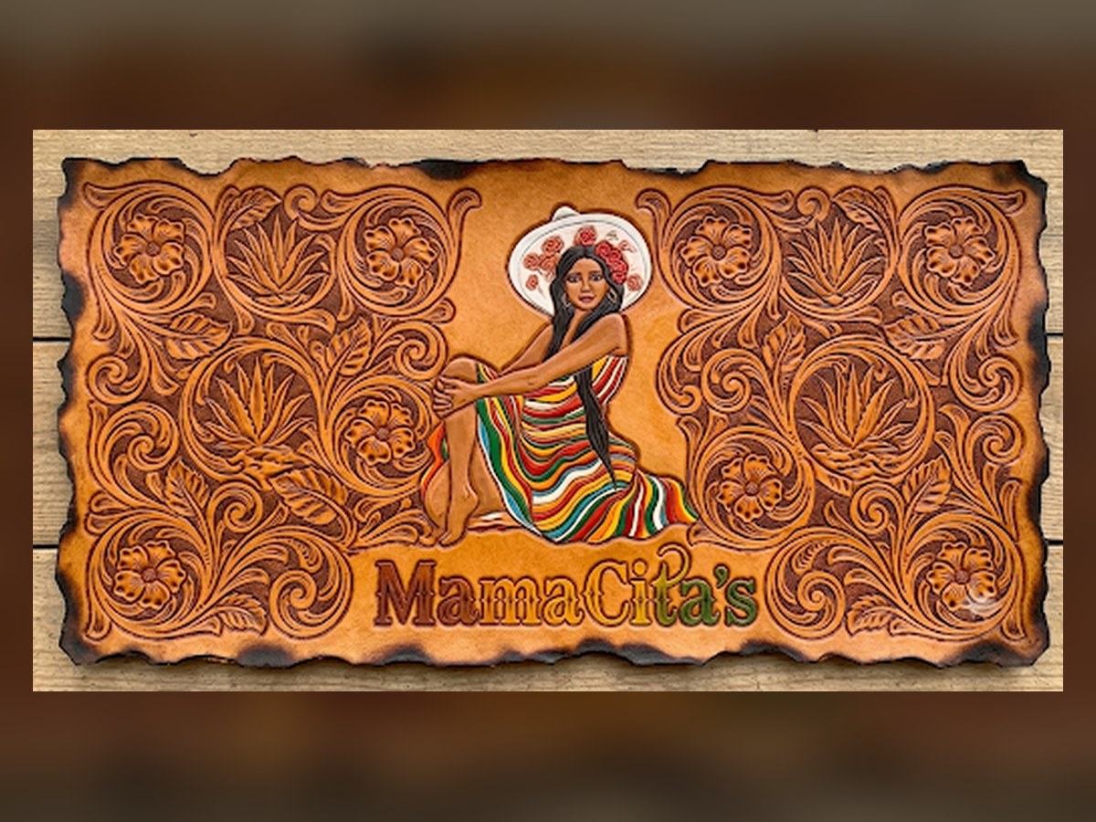 MamaCita's sign designed to look like hand-tooled leather, with a woman in a sombrero and serape framed by carved floral tooling